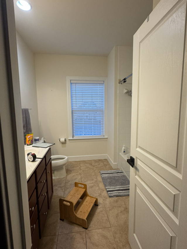 A kitchen with light wood cabinets, appliances, and a central island. A window is in the back.