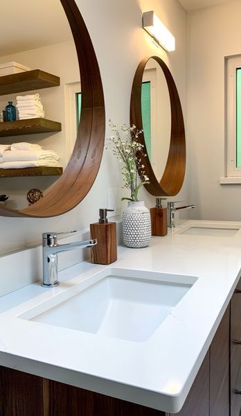 Modern bathroom with dual sinks, wooden-framed mirrors, white countertop, and floating shelves.