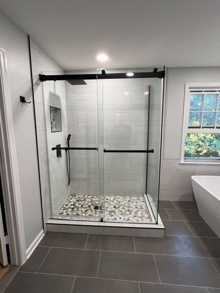 Modern bathroom with a glass shower enclosure and gray tile flooring.