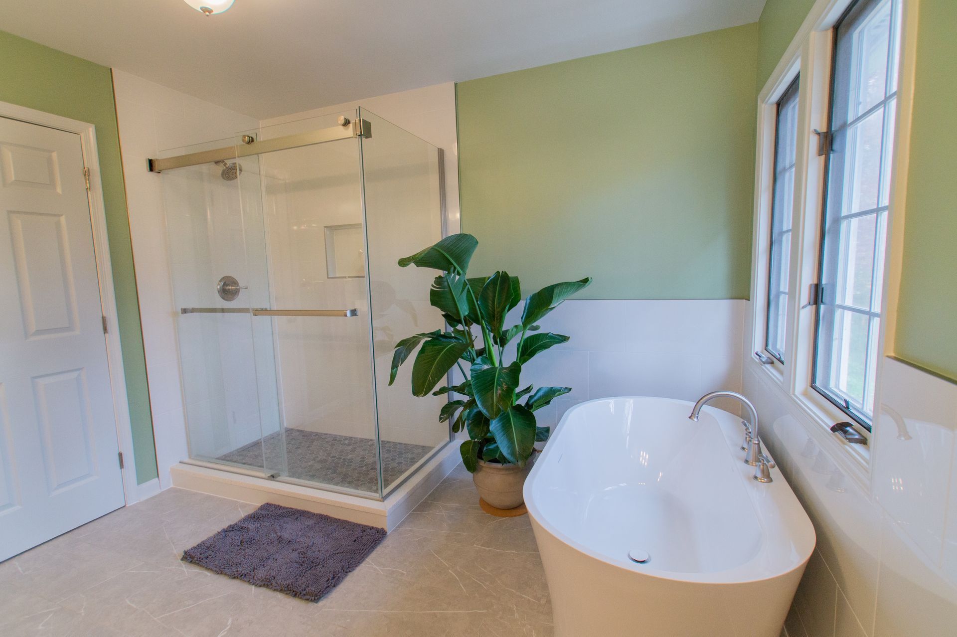 Bathroom with a walk-in shower, freestanding tub, and a large houseplant. Walls are green and white.