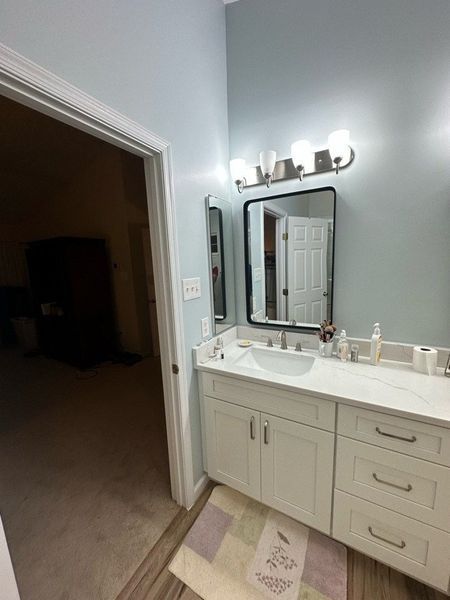 Bathroom with a white vanity, a square mirror, and light blue walls.