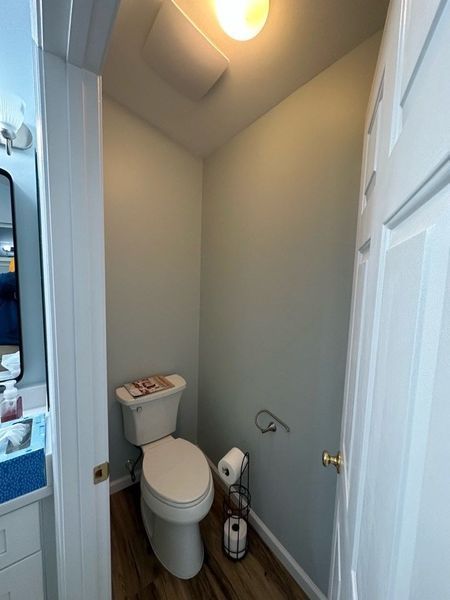 Small bathroom with a toilet, roll of toilet paper, and blue-green walls.