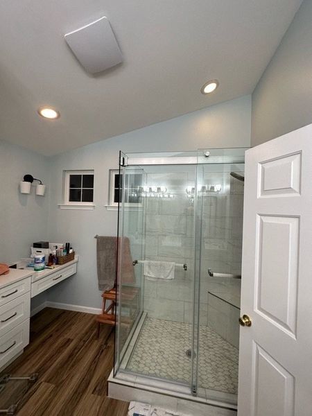 Bathroom with shower, vanity, and door. Blue walls, brown floor, glass shower door.