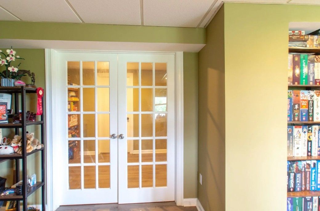 Double glass-paned doors with white frames leading into a room; green and beige walls; bookshelf on the right.