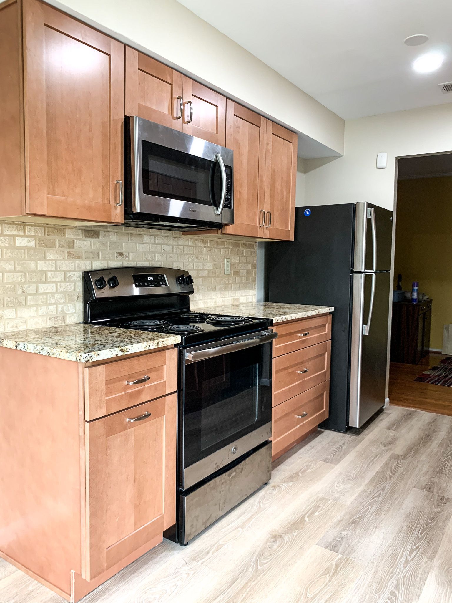 Kitchen with light brown cabinets, stainless steel appliances, and a tiled backsplash.