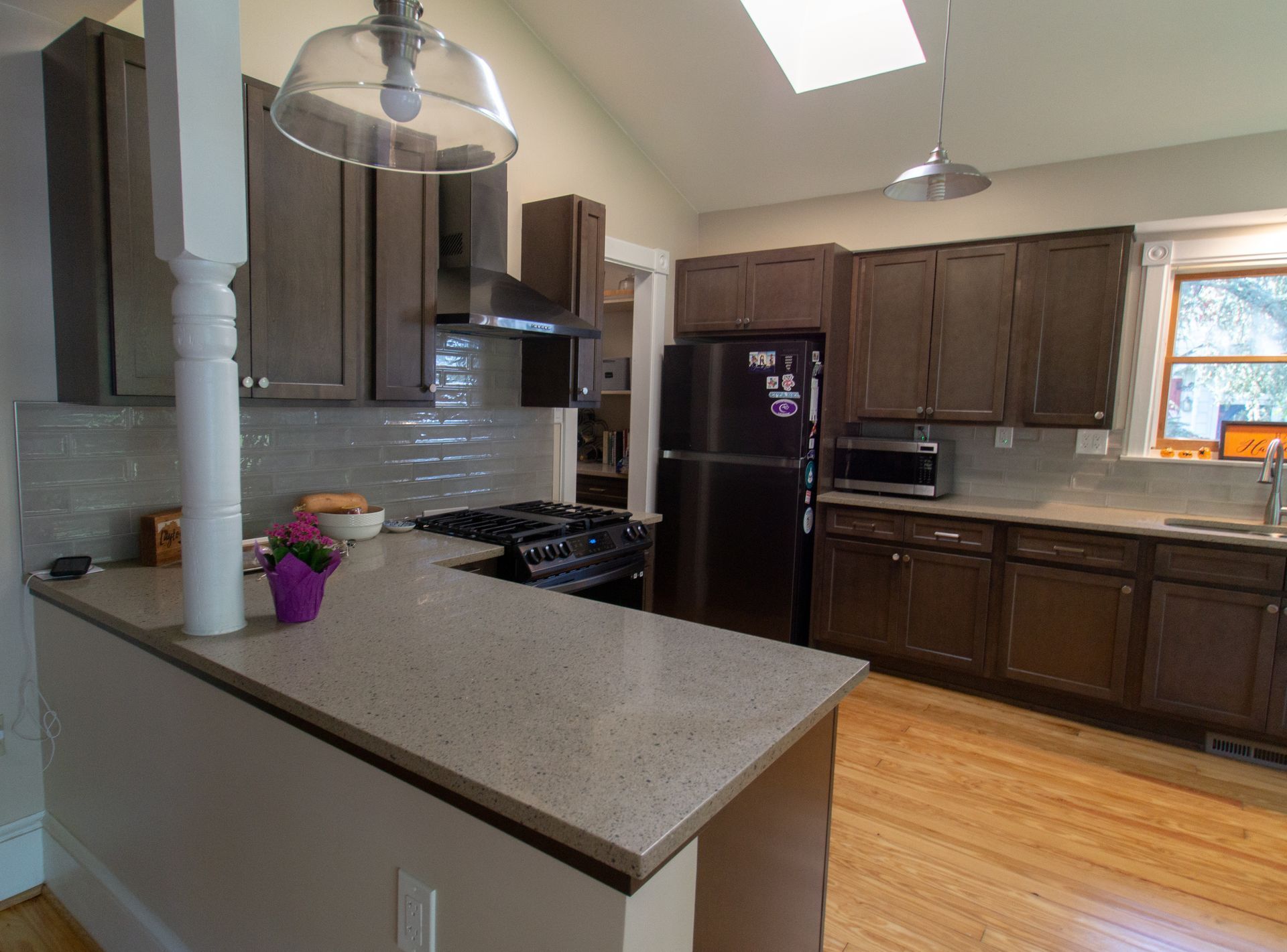 Kitchen with dark brown cabinets, light countertops, and wood floors.