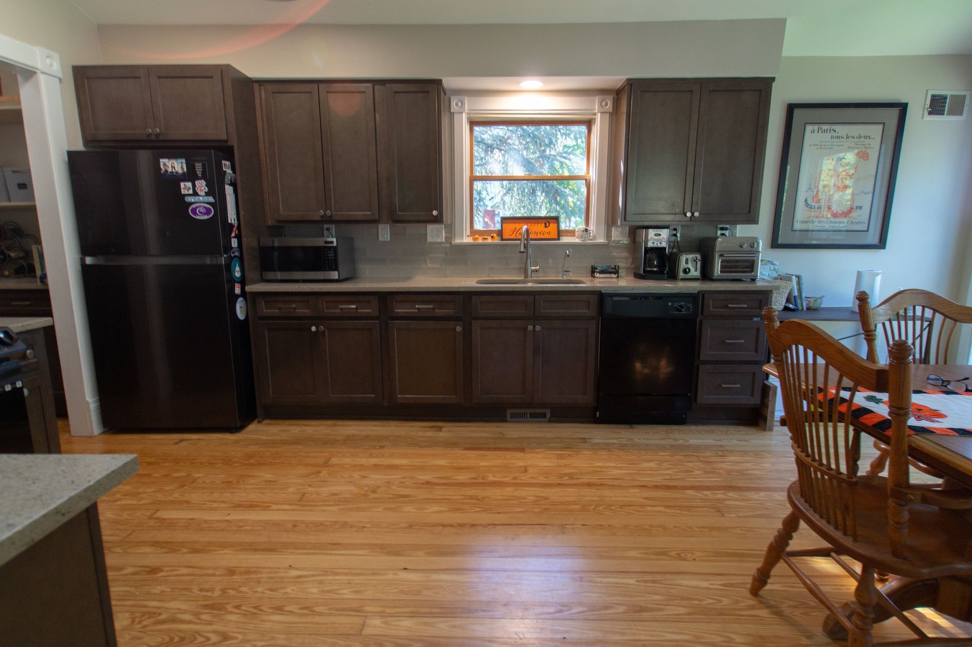 Kitchen with brown cabinets, stainless steel appliances, and wooden floor. A window is above the sink.