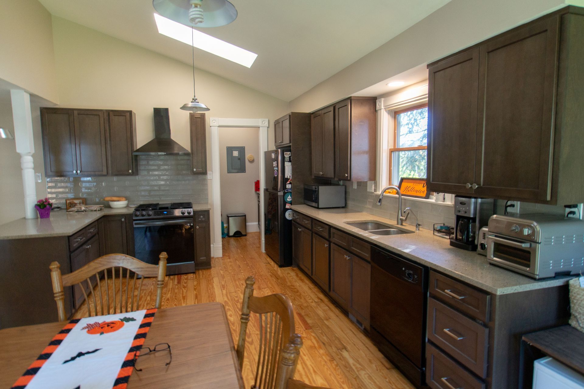 Kitchen with brown cabinets, light countertops, wood floor, and Halloween table runner.