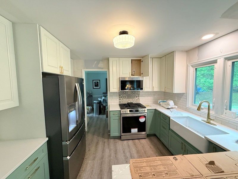 Kitchen with green and cream cabinets, stainless appliances, and farmhouse sink.