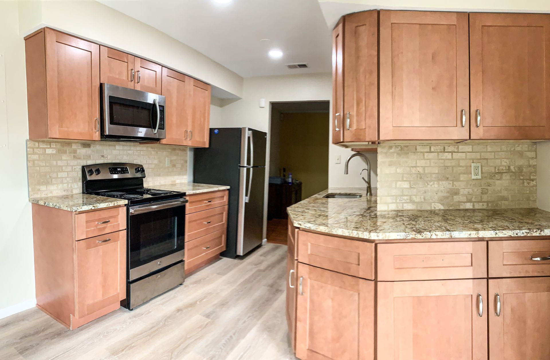 Kitchen with light brown cabinets, stainless steel appliances, and a curved countertop.