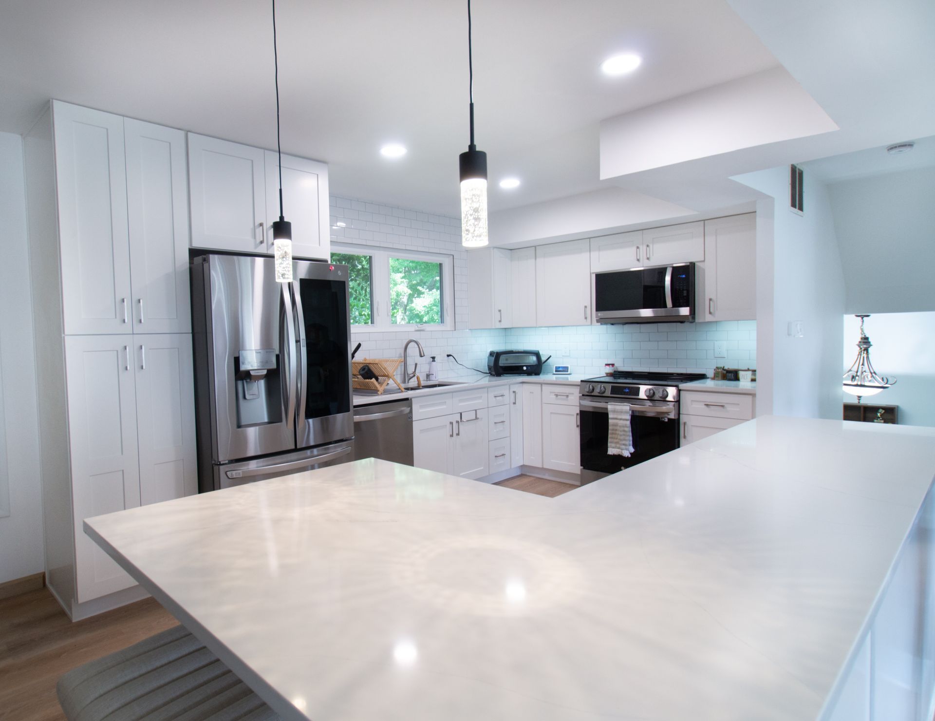 White modern kitchen with stainless steel appliances and a white countertop.