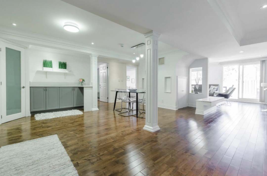 Bright, modern interior with hardwood floors. Features a dining area, a seating area, and a built-in cabinet.