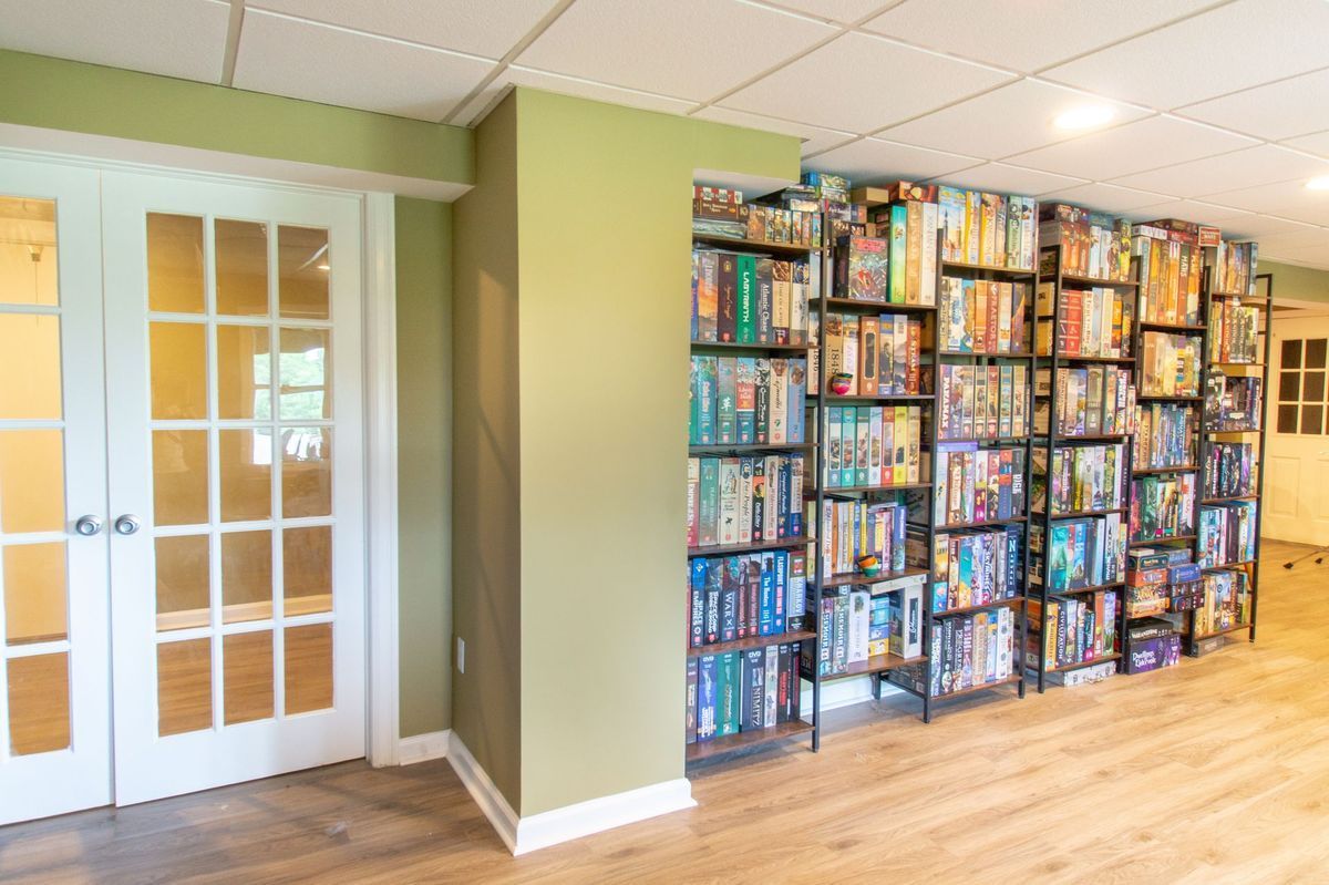 Basement room with glass-paned doors and a wall of shelves stacked with DVDs and Blu-ray discs.