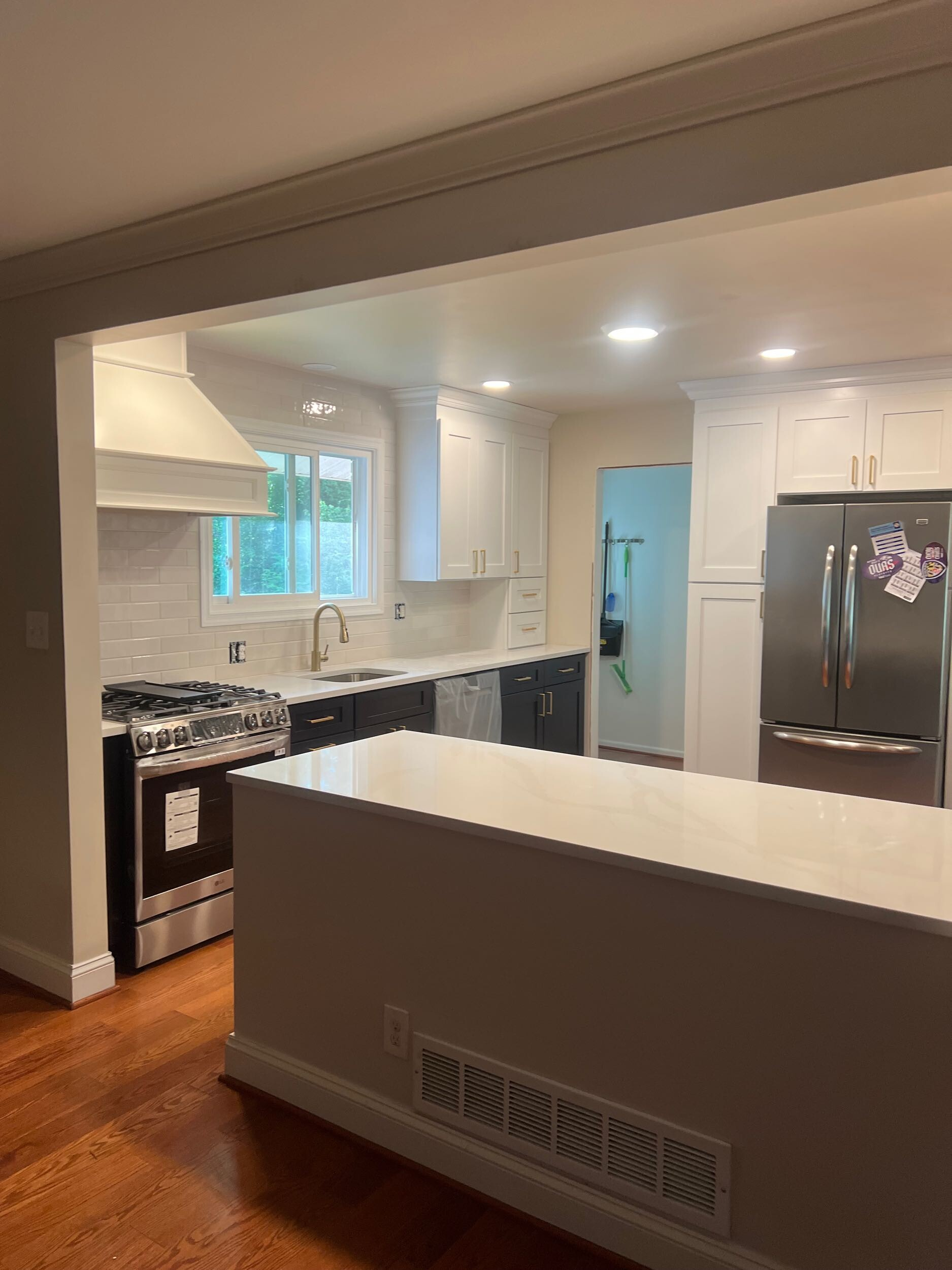 White kitchen with island, stainless steel appliances, and wood-look flooring.