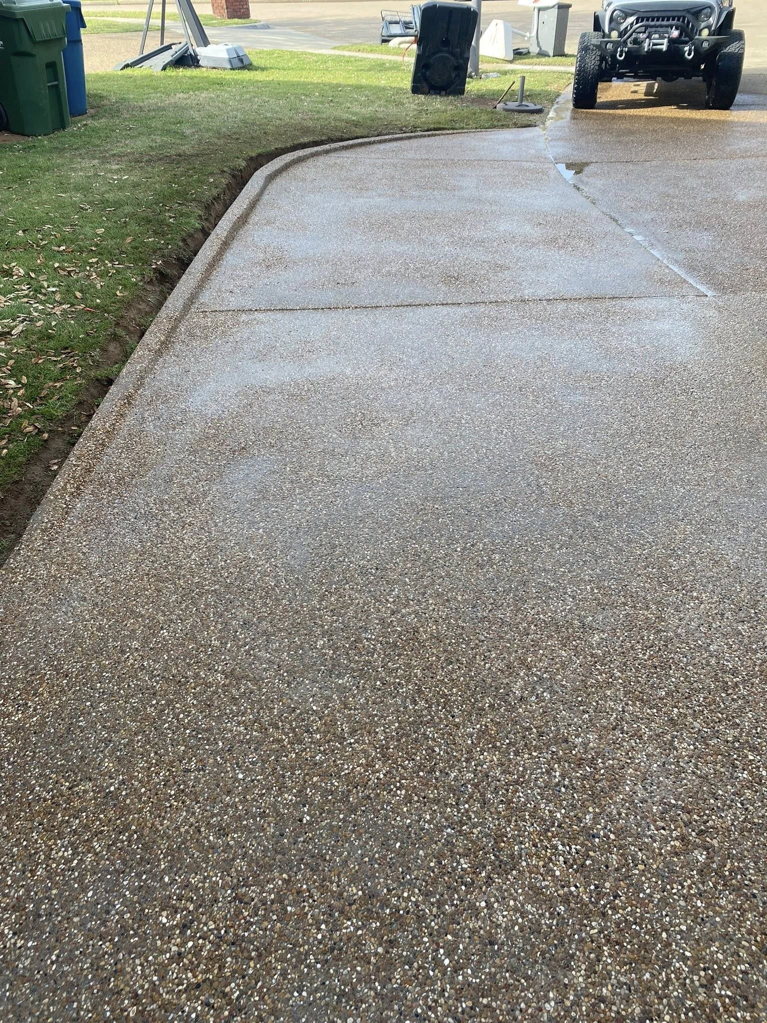 A gravel driveway curves away from the viewer; a dark jeep is parked at the end near green grass.