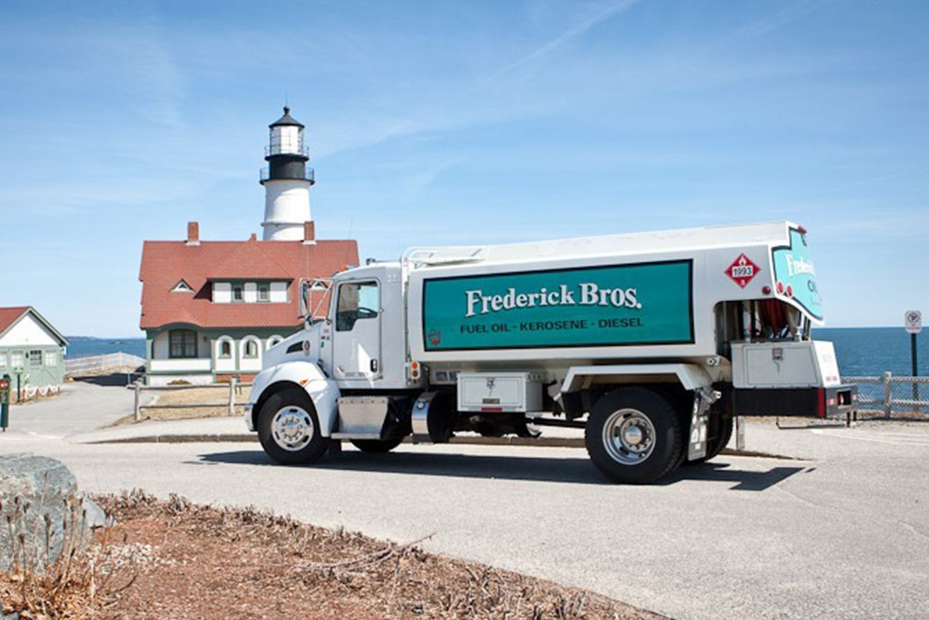 A frederick bros truck is parked in front of a lighthouse