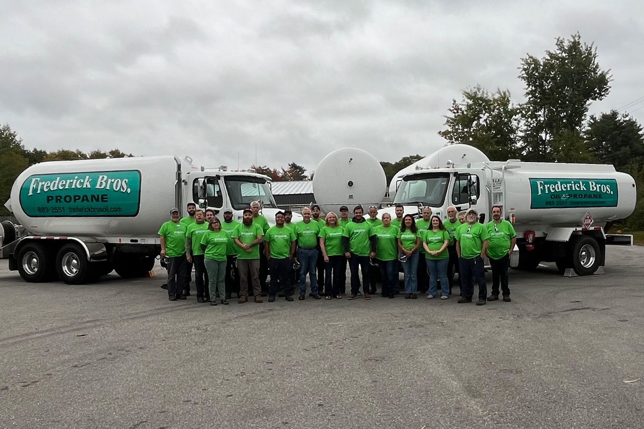 A group of people standing in front of trucks that say frederick bros