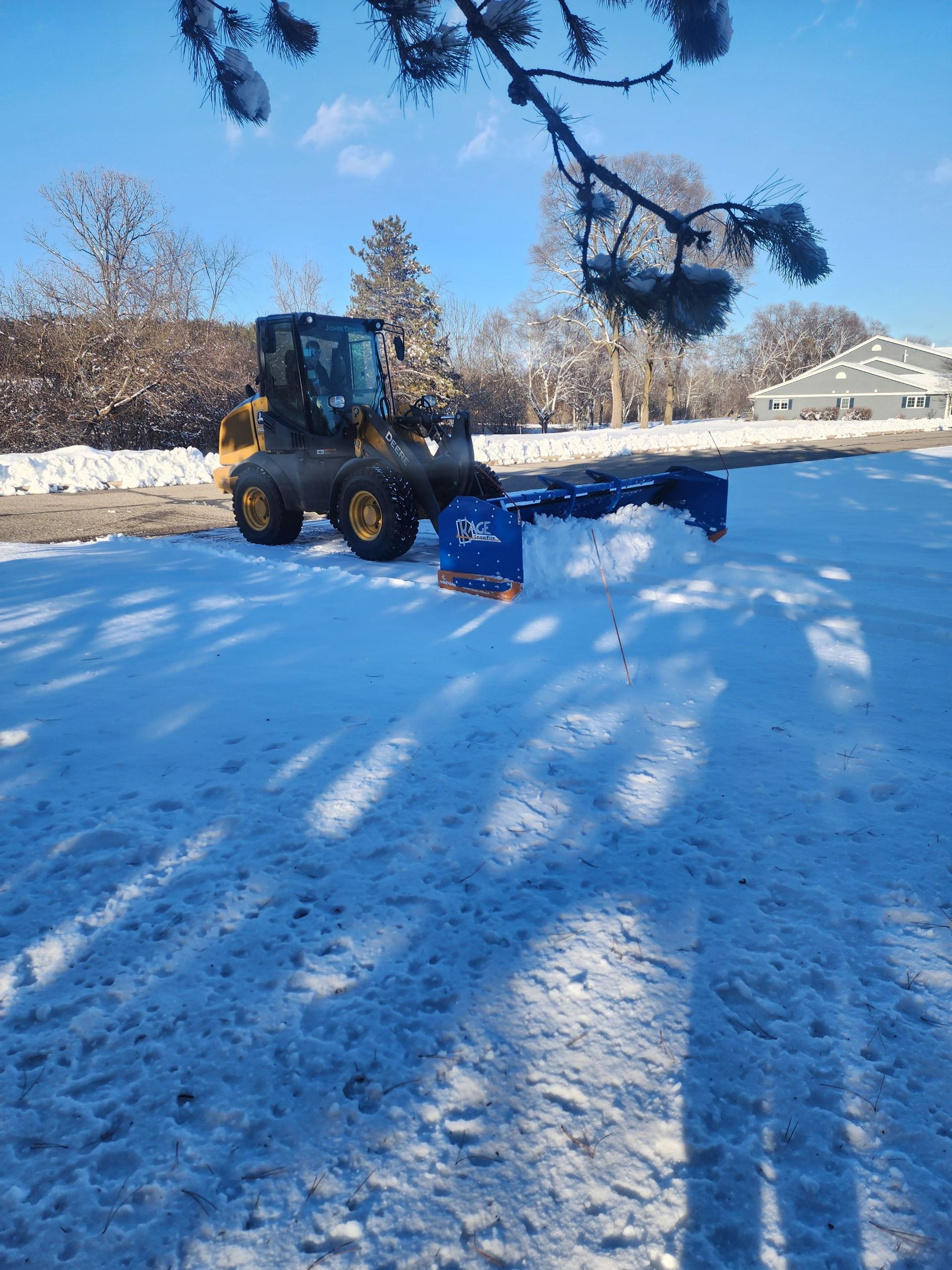 A snow plow is sitting in the snow in a parking lot.