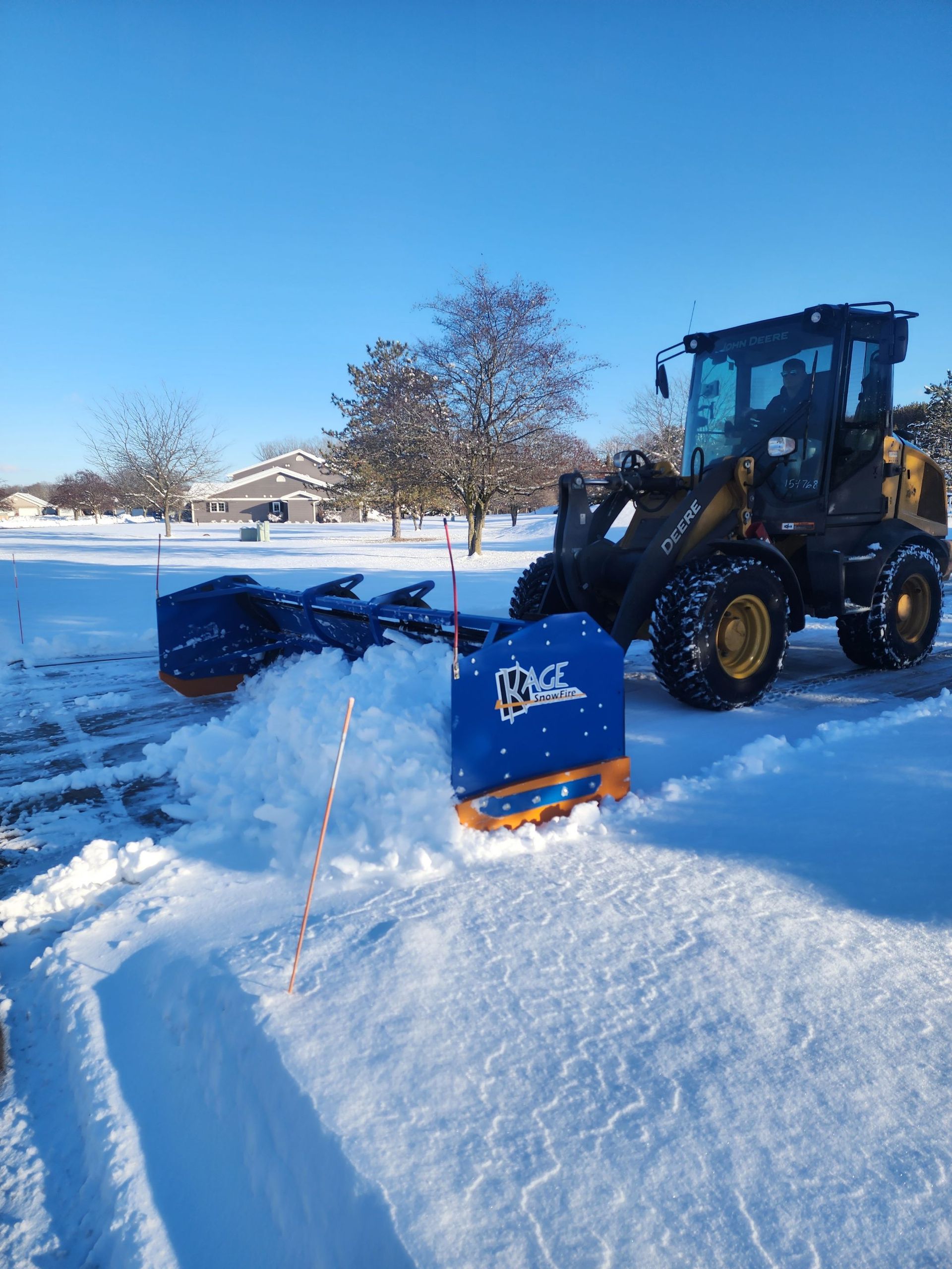 A snow plow is clearing snow from a parking lot
