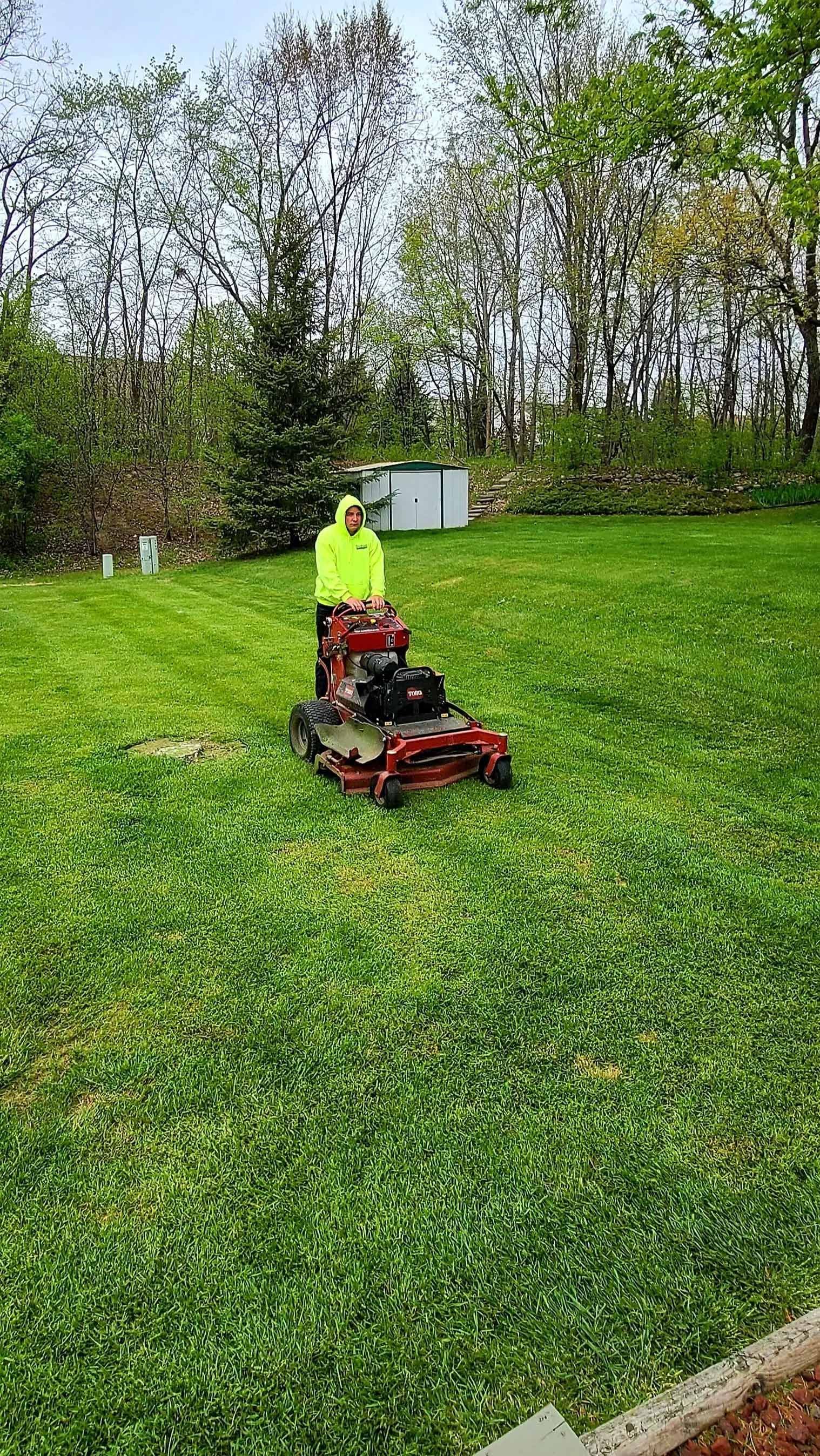 A man is riding a lawn mower on a lush green lawn.
