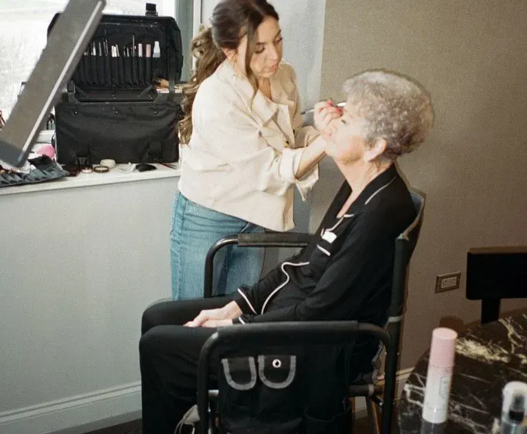 Makeup artist applying makeup to seated client in a salon chair