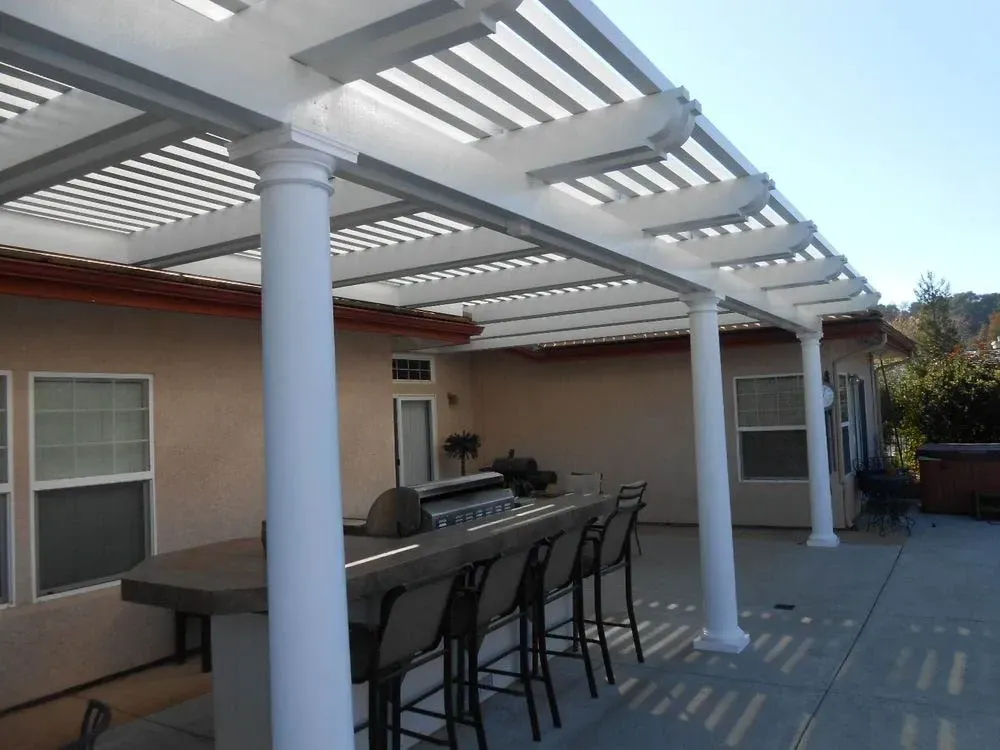 A patio with a pergola and a table and chairs