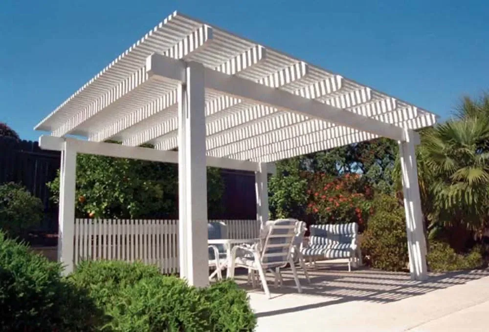 A white pergola with a table and chairs underneath it