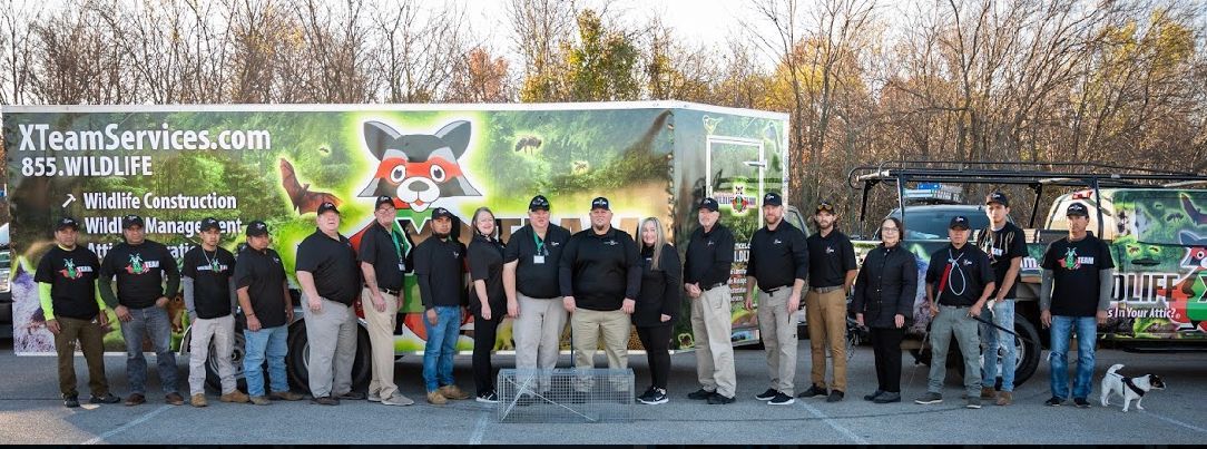 Group of people standing outdoors in front of a colorful Halloween-themed banner and display.