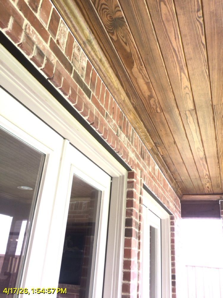 Covered porch ceiling above white-framed glass doors and a brick wall.