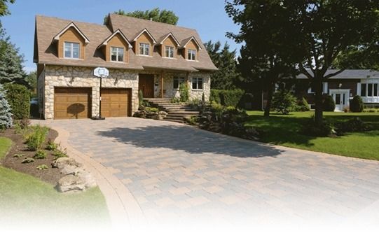 Two-story house with stone facade, brown roof, and driveway.