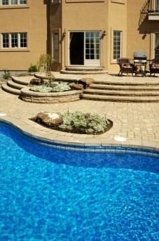 Swimming pool and patio with a light brown house in the background.