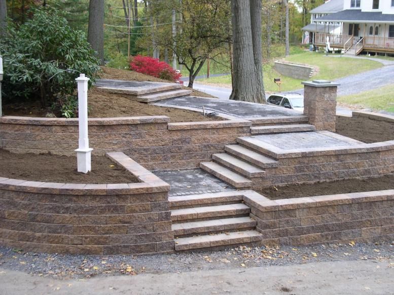 Stone retaining walls and steps leading up a hillside in a residential area.