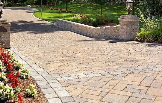 Paver driveway with a curved path, retaining wall, and landscaping.
