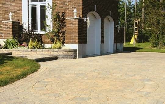 Brick house with arched garage doors, a paved driveway with a circular design, and landscaping.