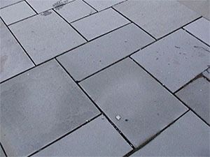 Gray stone paving with dark lines between the rectangular blocks.