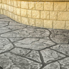 A concrete walkway with a brick wall in the background