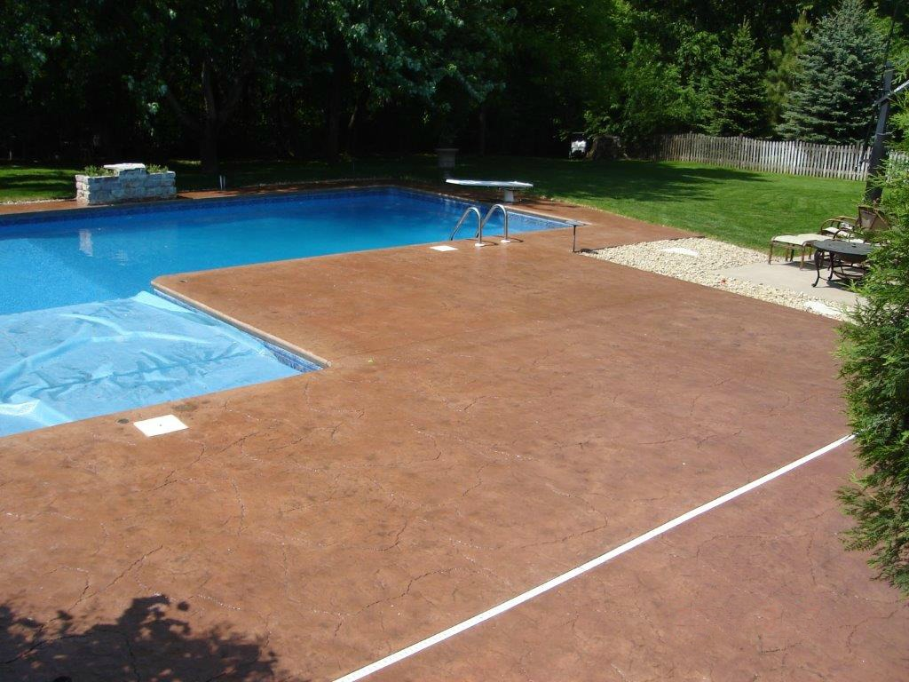 A large swimming pool with a red concrete deck