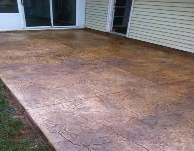 A concrete patio in front of a house with a sliding glass door