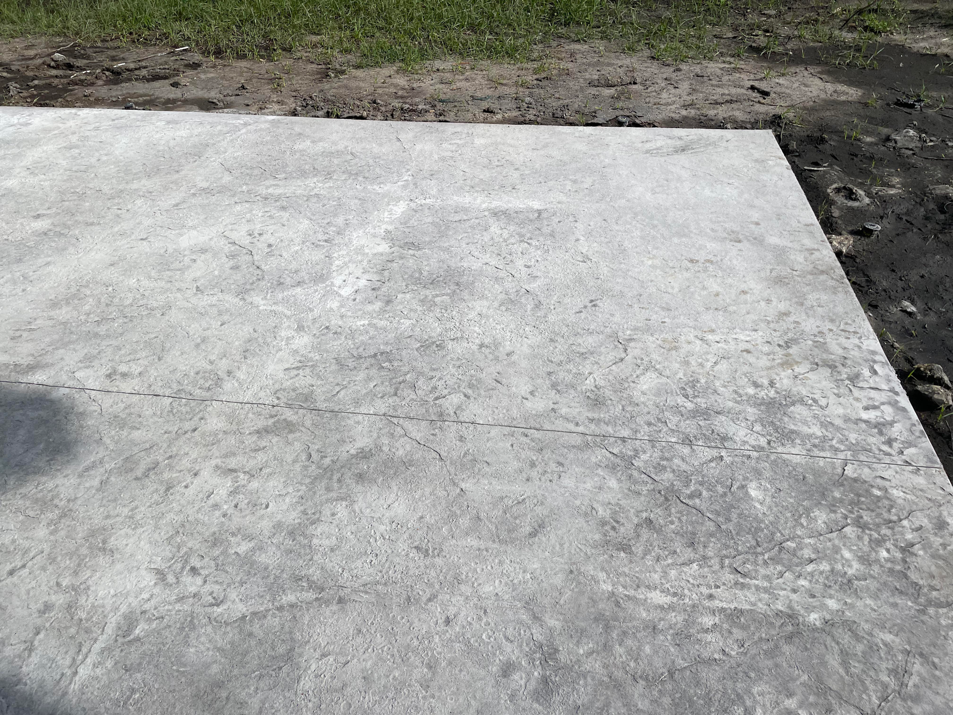 A close up of a concrete driveway with grass in the background