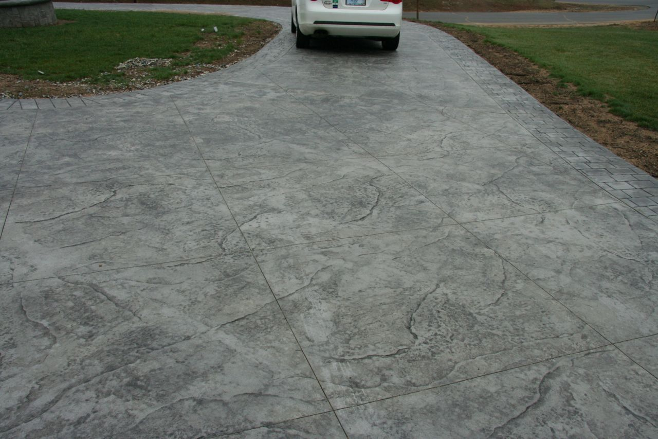 A white car is parked in a concrete driveway