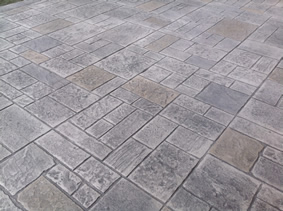 A close up of a concrete driveway with a pattern of bricks