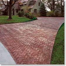 There is a brick driveway leading to a house