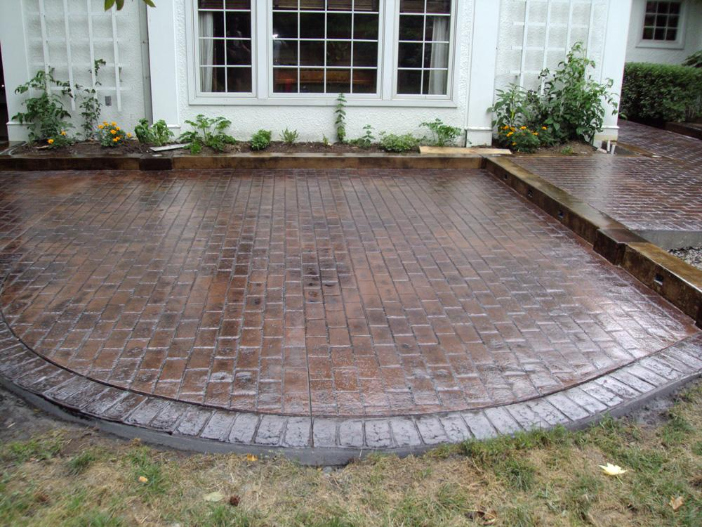 A brick patio in front of a white house