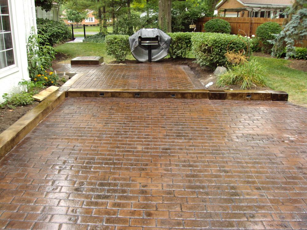 A brick driveway with a grill in the background