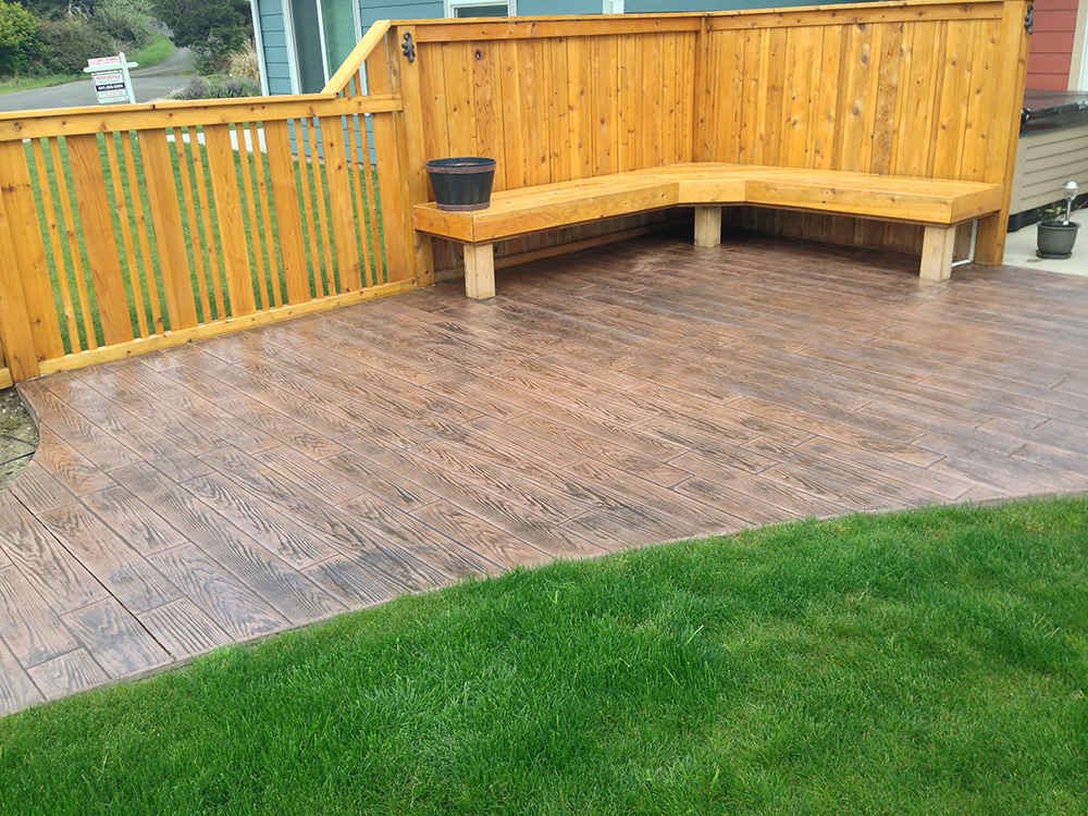 A wooden deck with a bench and a fence in the backyard