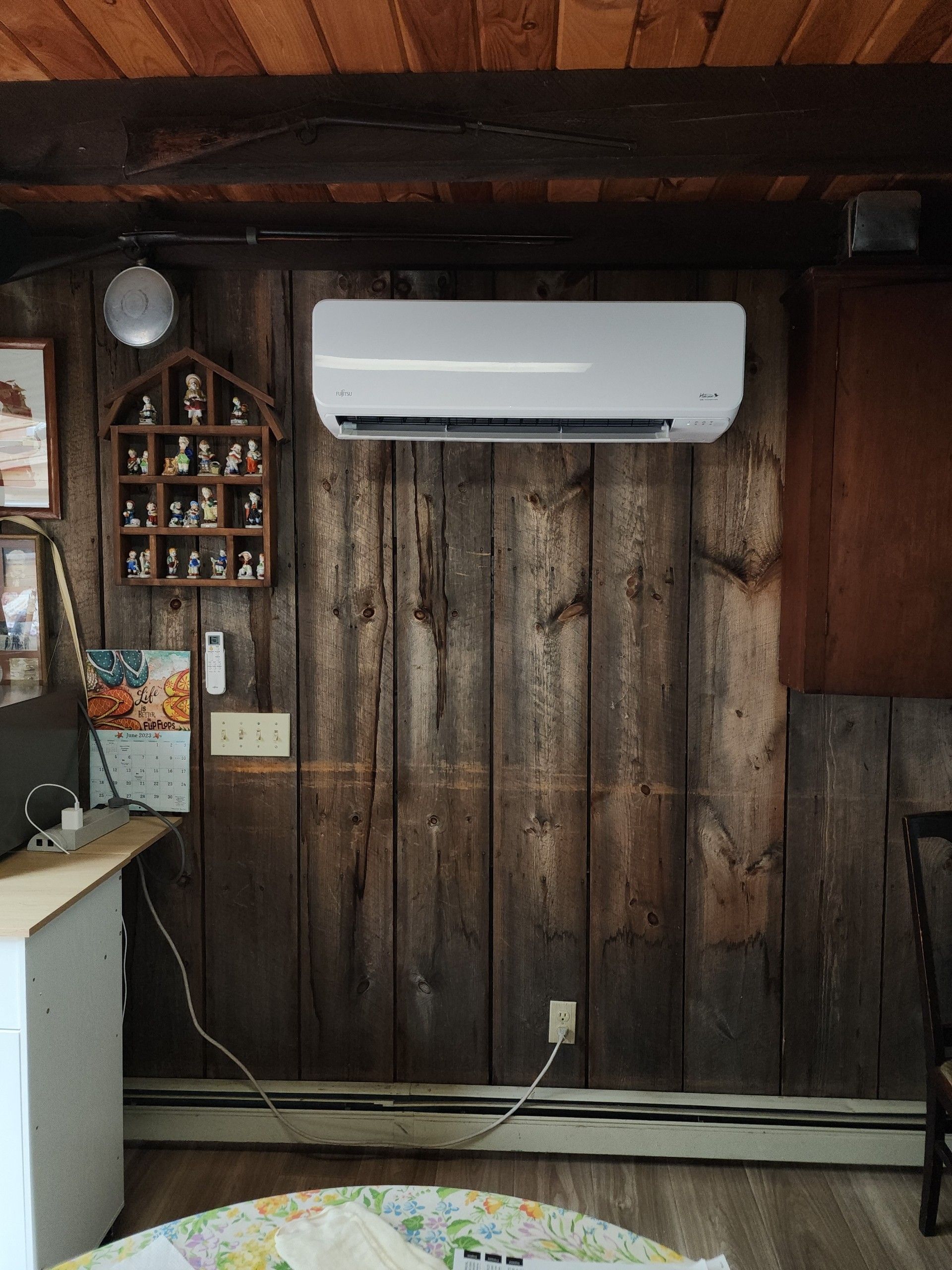 White wall-mounted air conditioner on a rustic wood wall above a kitchen counter