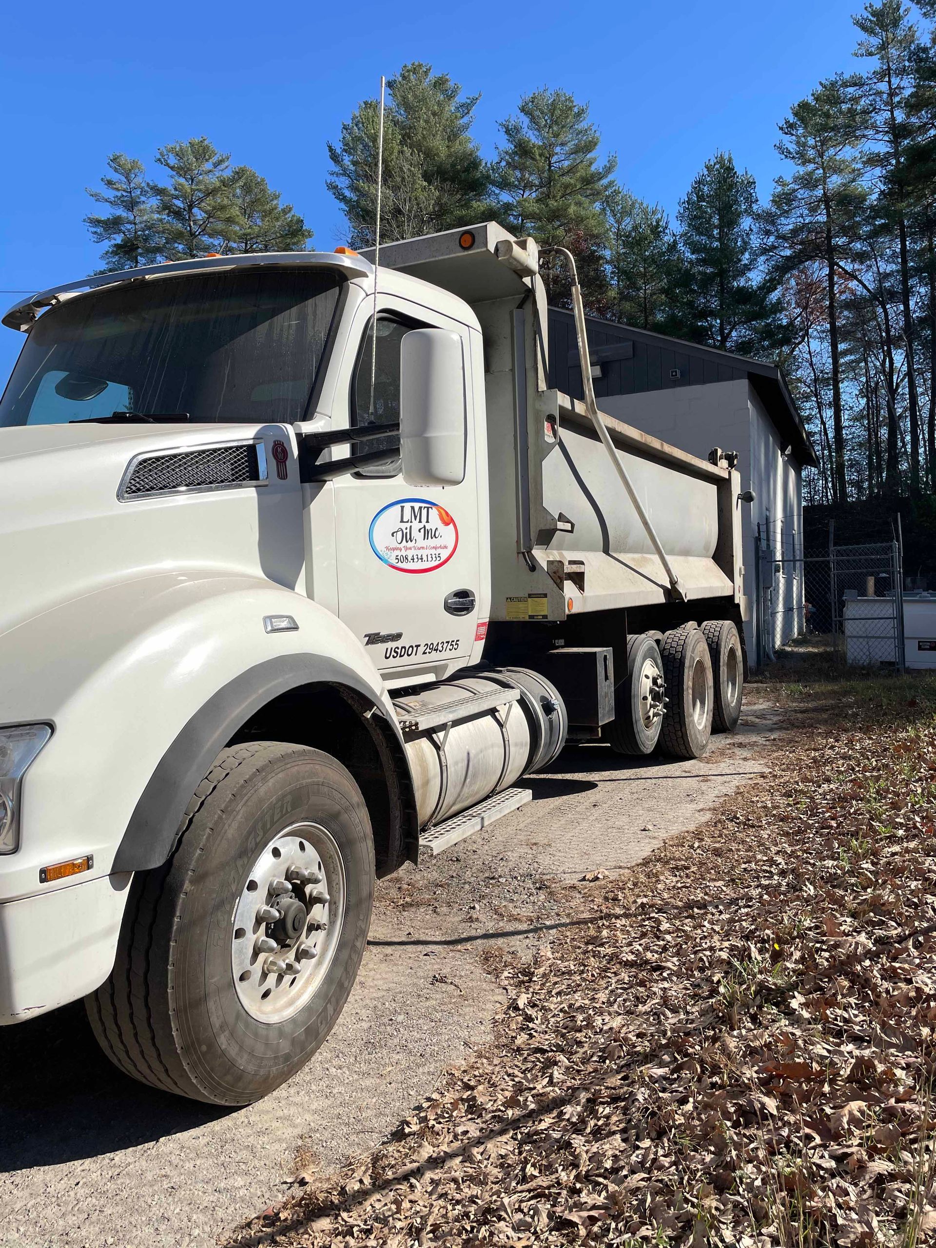 A white dump truck is parked on the side of the road.