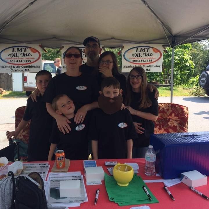 A group of people posing for a picture under a tent that says lmt