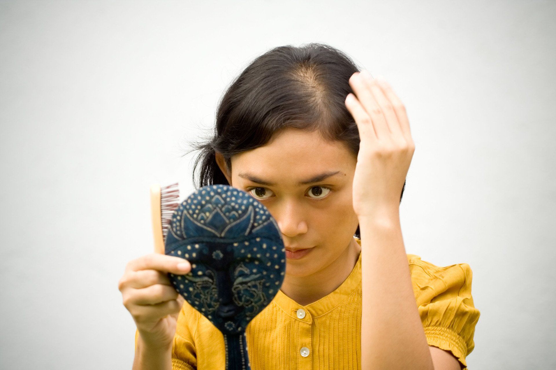 A woman is brushing her hair in front of a mirror.