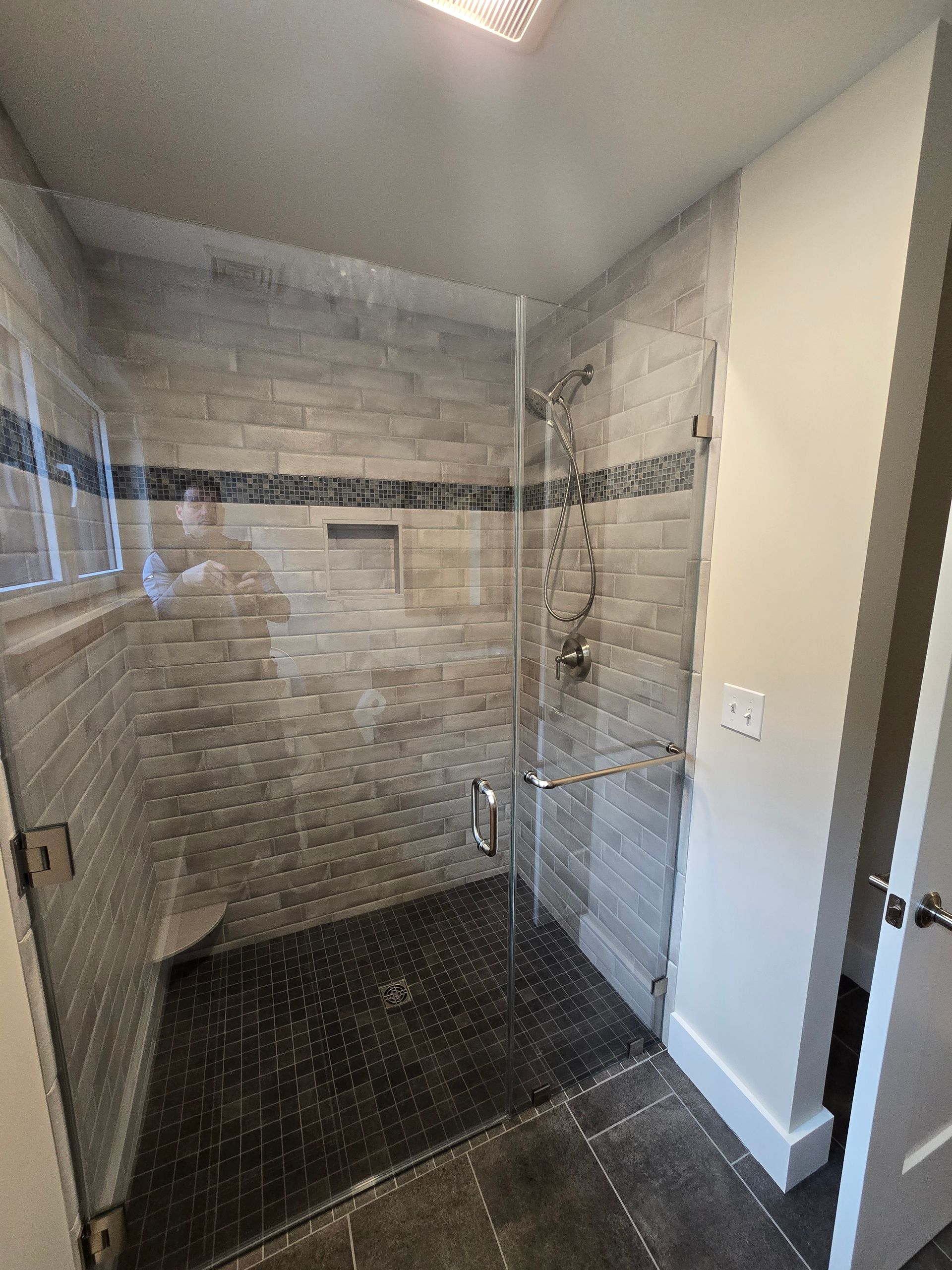 A bathroom with a walk in shower with a glass door.